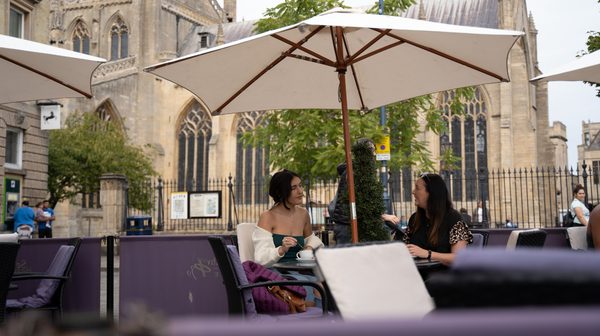 women sat under al fresco dining area with coffees and boston stump in the background