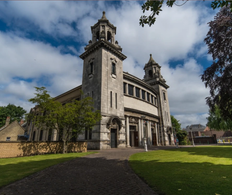 wide angle image of centenary Methodist church with green grass and blue skies