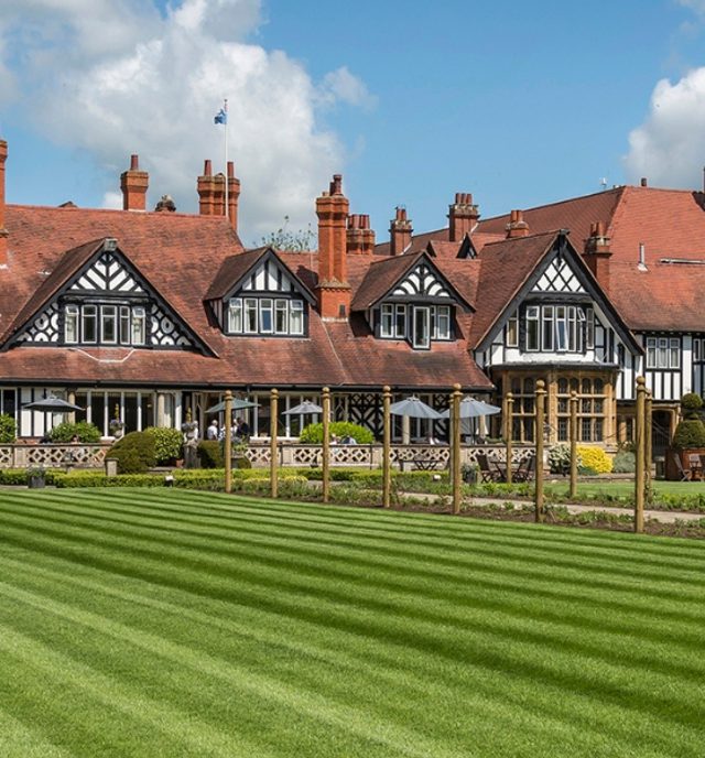 exterior of Petwood Hotel under blue skies with freshly mowed green grass in the foreground
