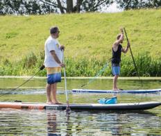 2 men Stand Up Paddleboarding on a river
